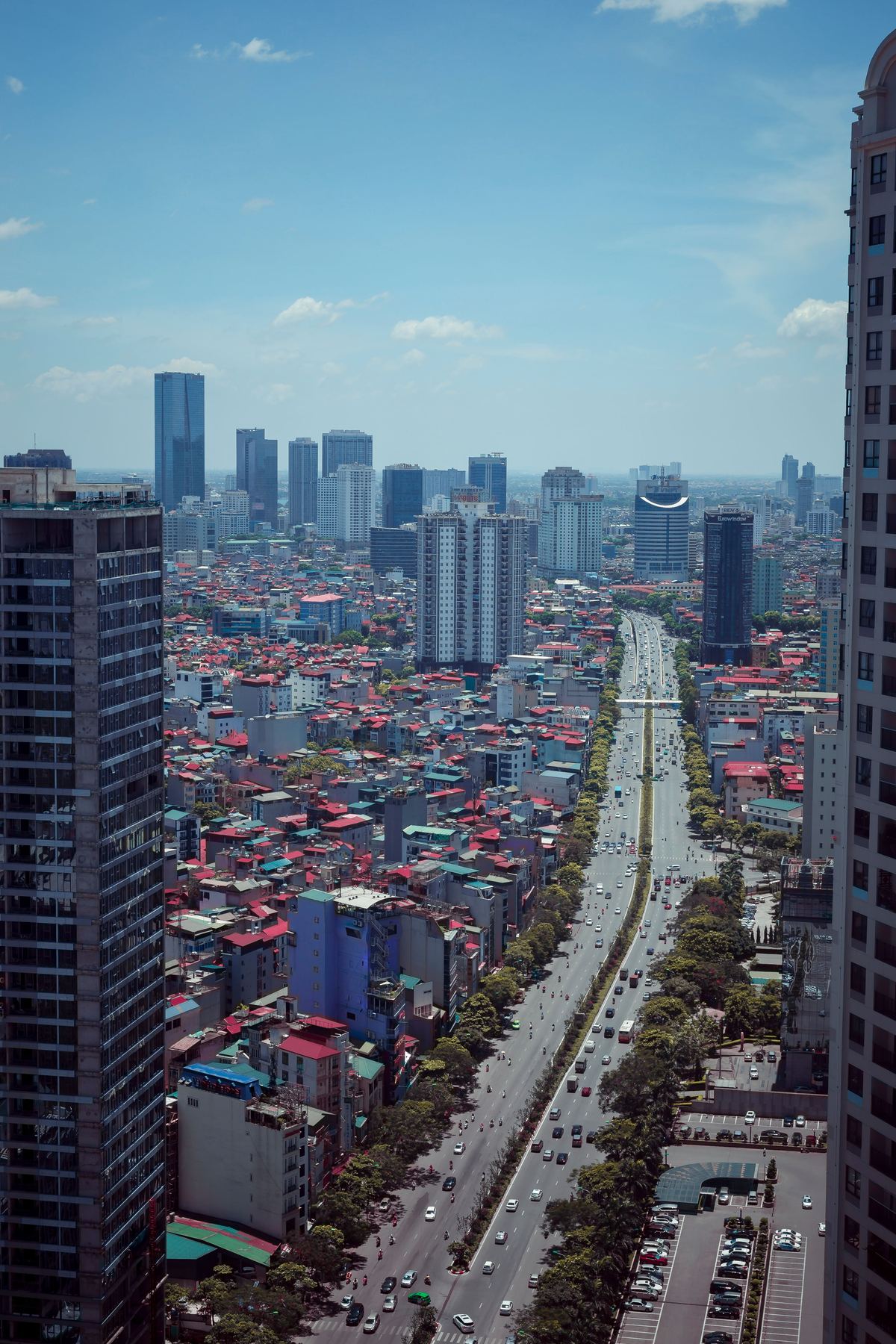 Aerial view of Hanoi, with low-rise neighbourhoods and office towers along a main avenue